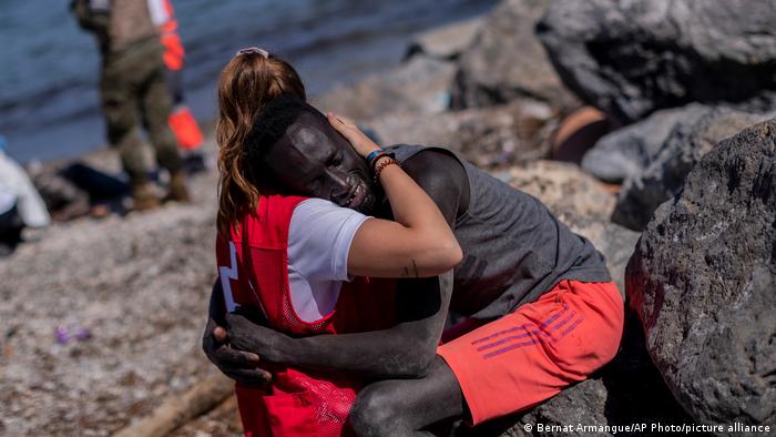 Chica de cruz roja abrazando a un migrante